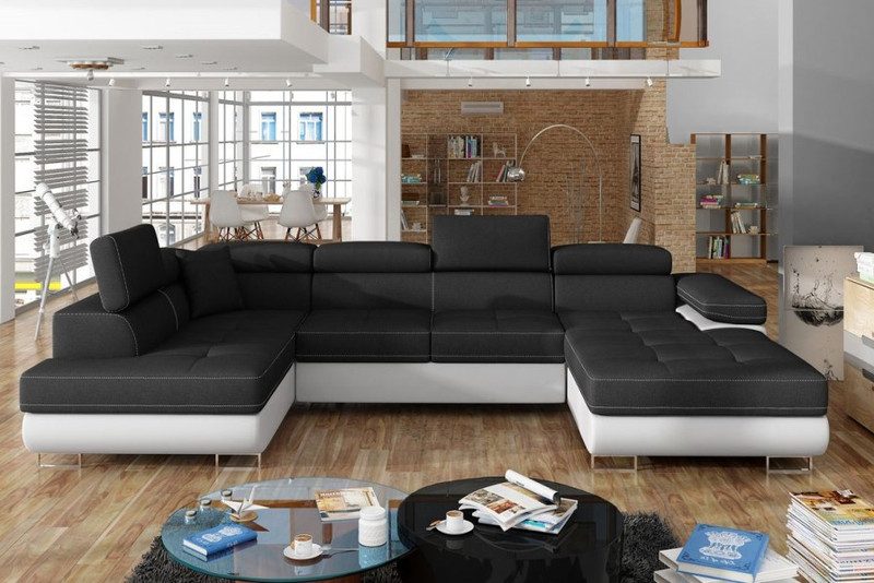 Vandermere U-shaped corner sofa bed with black seats and back on a white base, headrests and a chaise end on each side, in an open-plan loft with tall windows and a brick wall