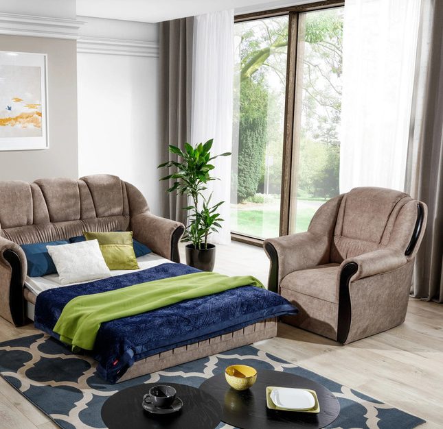 Mink-brown Quenby sofa bed opened out and made up with a navy throw, green blanket and cushions, beside a matching armchair in a bright room