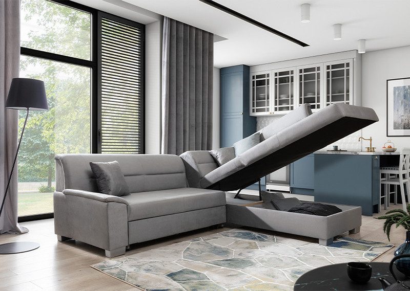 Grey Mistral corner sofa bed with the right-hand chaise seat raised to show a storage compartment with a dark blanket inside