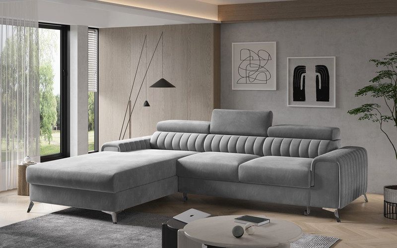 Grey Inverleigh corner sofa bed with a channel-stitched back and the chaise on the left, against a plain grey wall beside a tall window