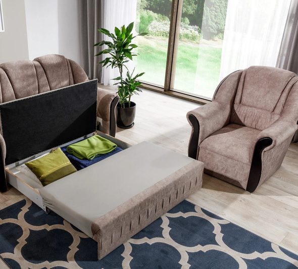 Quenby sofa bed with its storage compartment lifted open to show folded bedding and cushions inside, beside a matching armchair