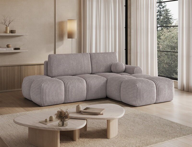 Grey Larkspur corner sofa bed with the chaise on the right, with two pale stone nesting coffee tables on a beige rug in front of the L-shape